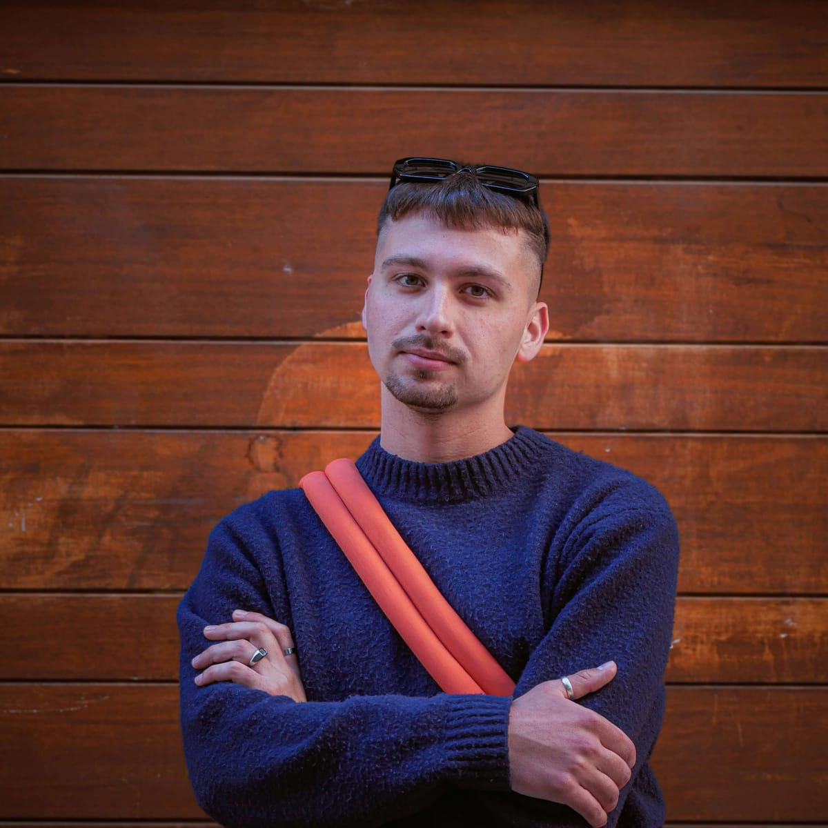 Man with arms crossed and sunglasses on head, looking satisfied