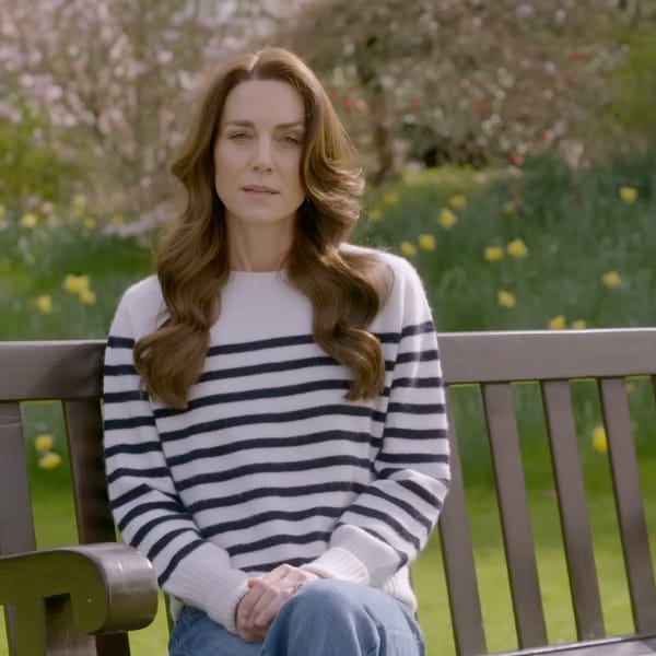 Woman in striped sweater sitting on bench in garden, looking serious
