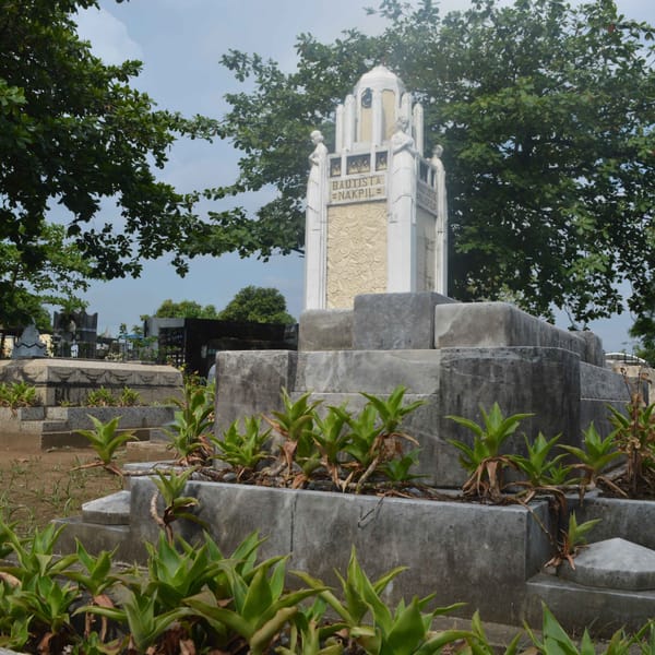 White monument with "Bautista Nakpil" inscription surrounded by trees and concrete structures in cemetery